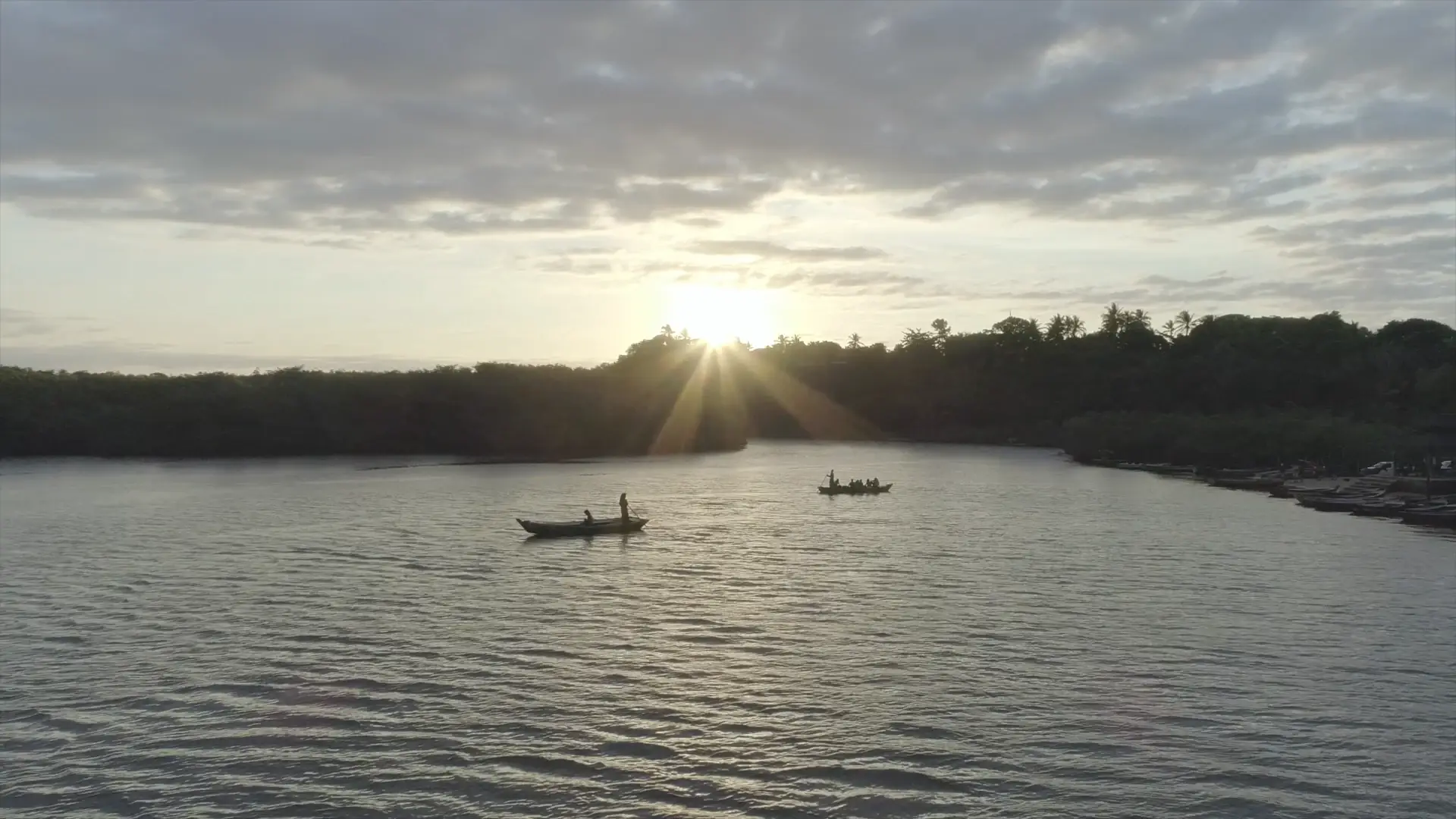 Duas canoas num rio do sul da Bahia, com o sol baixo atrás da mata